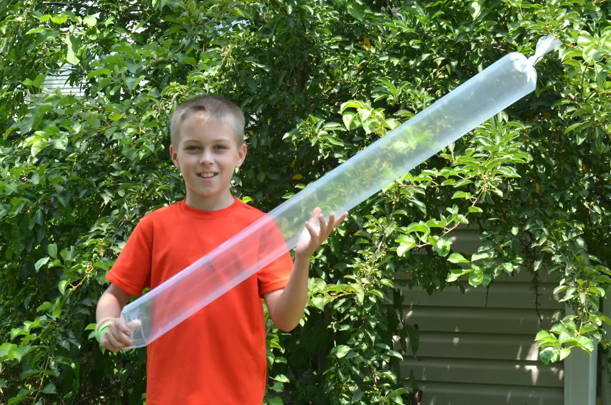 A boy holding the giant air rocket he built