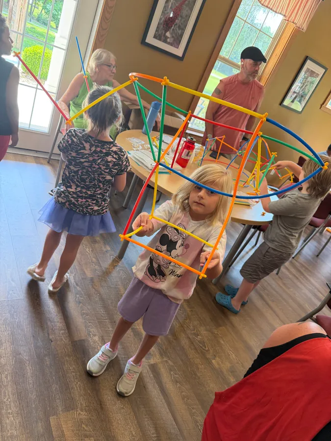 Children in a room building a large dome out of colourful straws and connectors