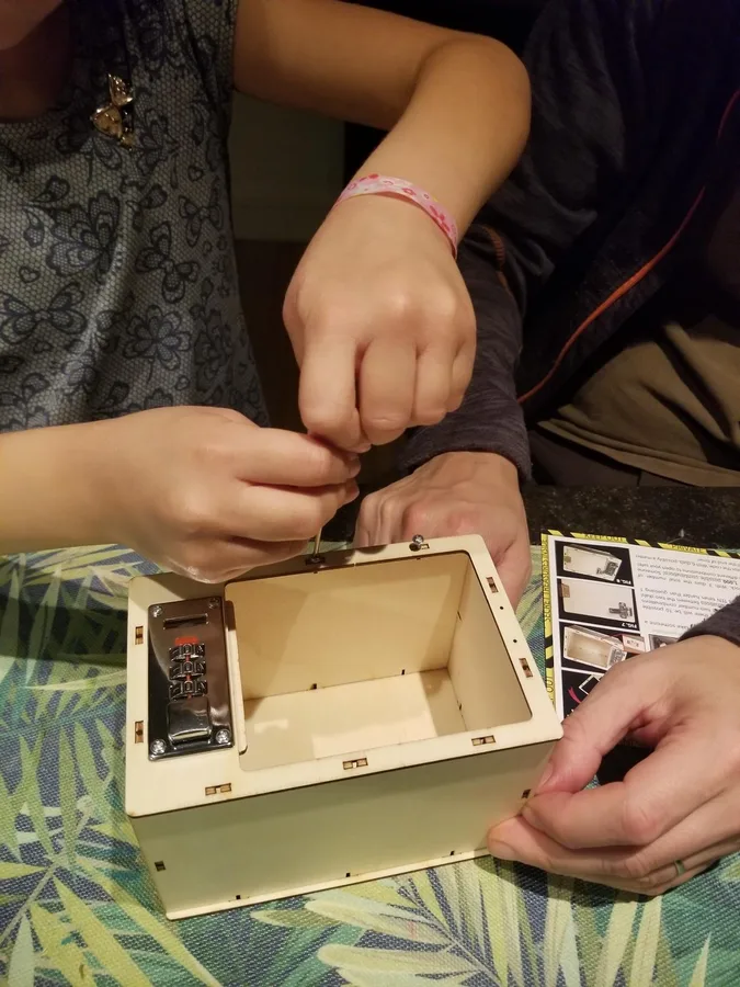 Hands assembling the wooden mechanical locking safe, its hinges and latch already fitted