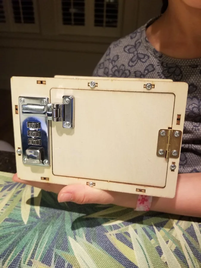 A child holding up the finished wooden locking safe they built