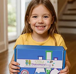 A girl smiling and holding her blue STEM Discovery Box