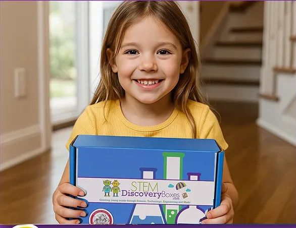 A smiling girl in a yellow shirt holding a blue STEM Discovery Box at her front door.