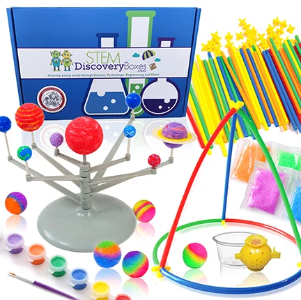 A STEM Discovery Box with a built solar system model, bouncy balls, paints and engineering straws laid out around it