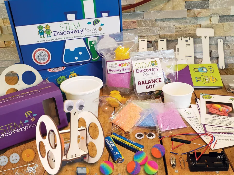 An open STEM Discovery Box with its three project kits and every pre-portioned supply laid out on a wooden table
