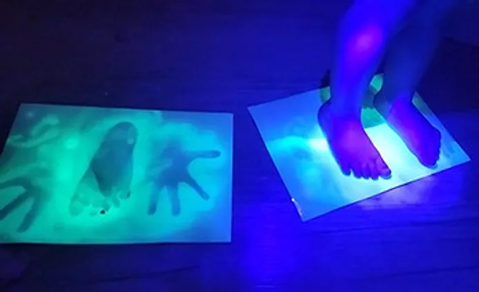 Glowing handprints on glow paper under a violet light