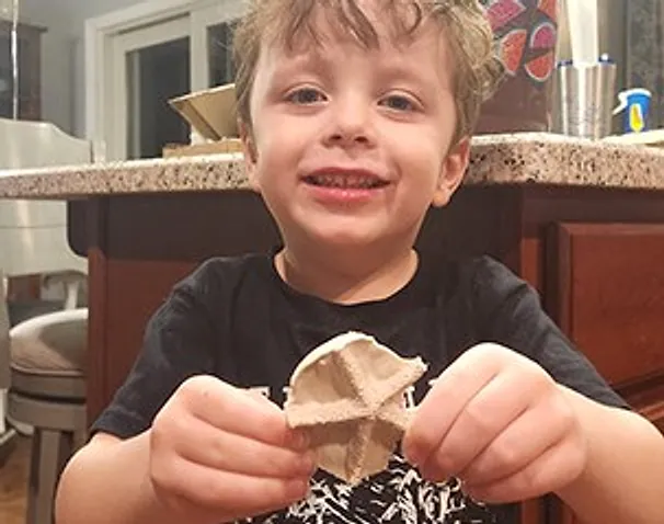 A smiling boy holding up the fossil casting he made