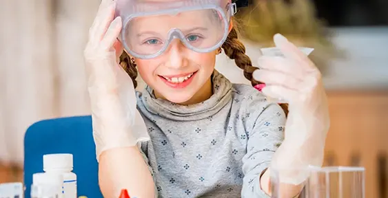 Two children in safety goggles running a hands-on science experiment together