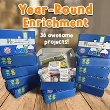 Stacked blue STEM Discovery Boxes, lettered Year-Round Enrichment, 36 awesome projects