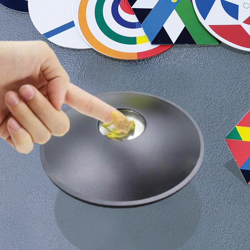A finger reaching for the floating 3D image above a black mirascope, with patterned optical-illusion disks beside it